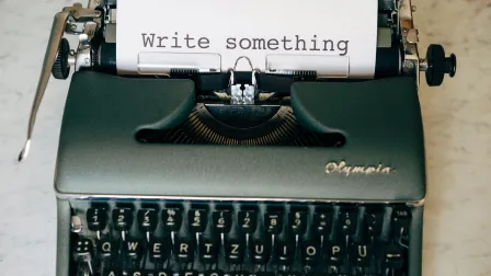 Image displays a typewriter with a sheet of paper that says 