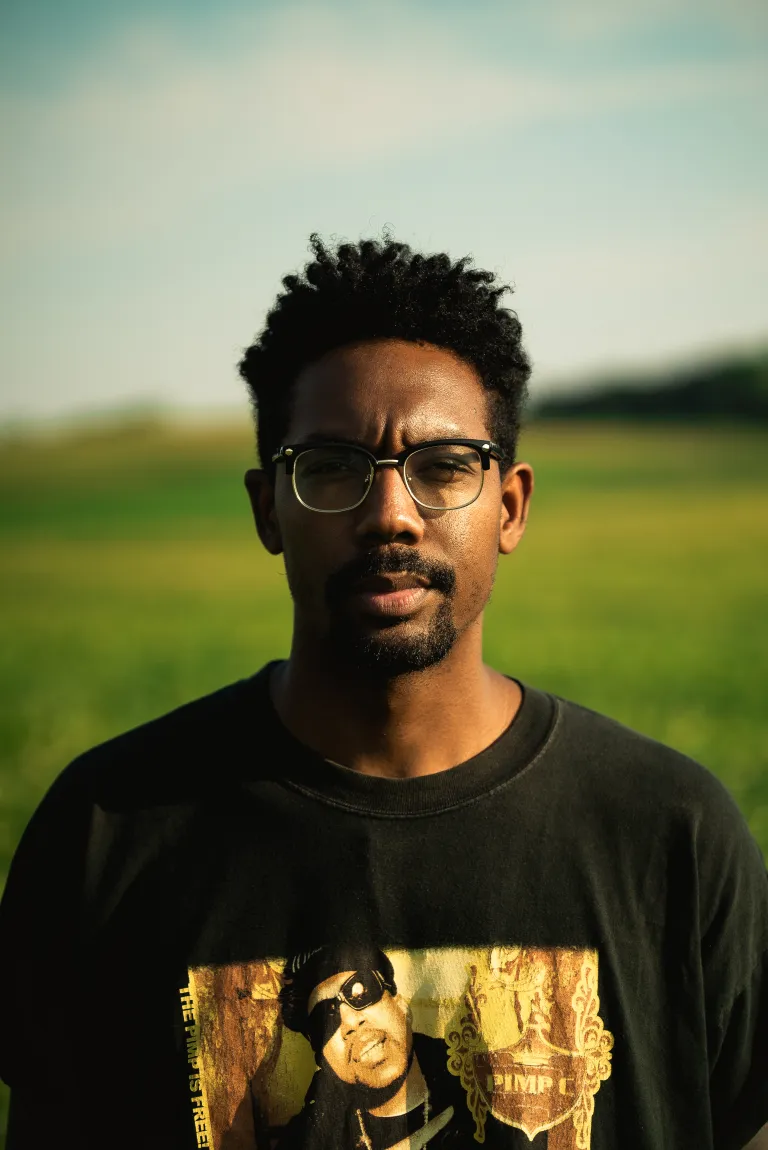a man in glasses wearing a black shirt in an outdoor setting