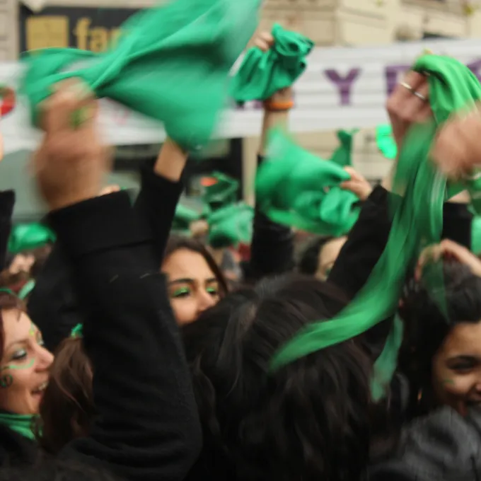 "Photo of a crowd of women waving green bandanas"