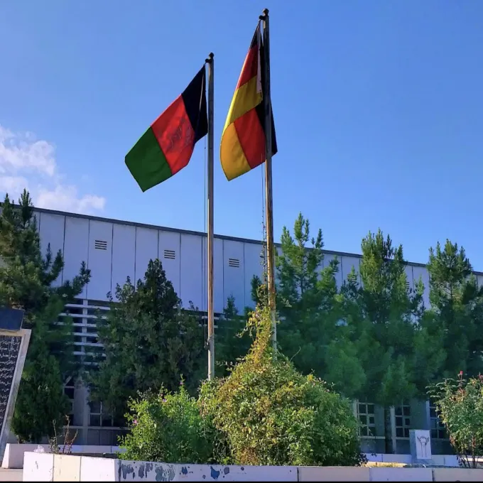 "flags of afghanistan and germany outside of a building"