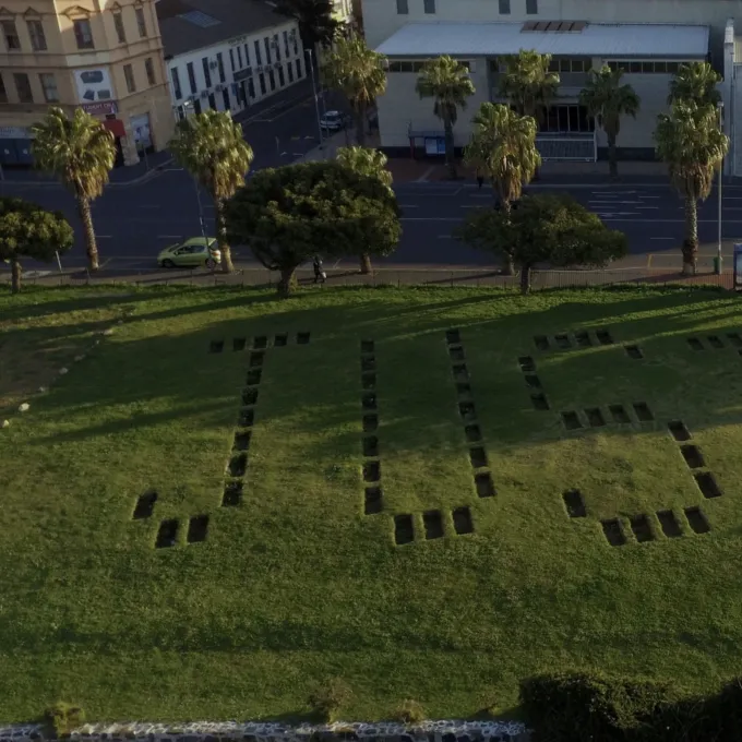 "coffin-size holes form letters to spell out the word justice"